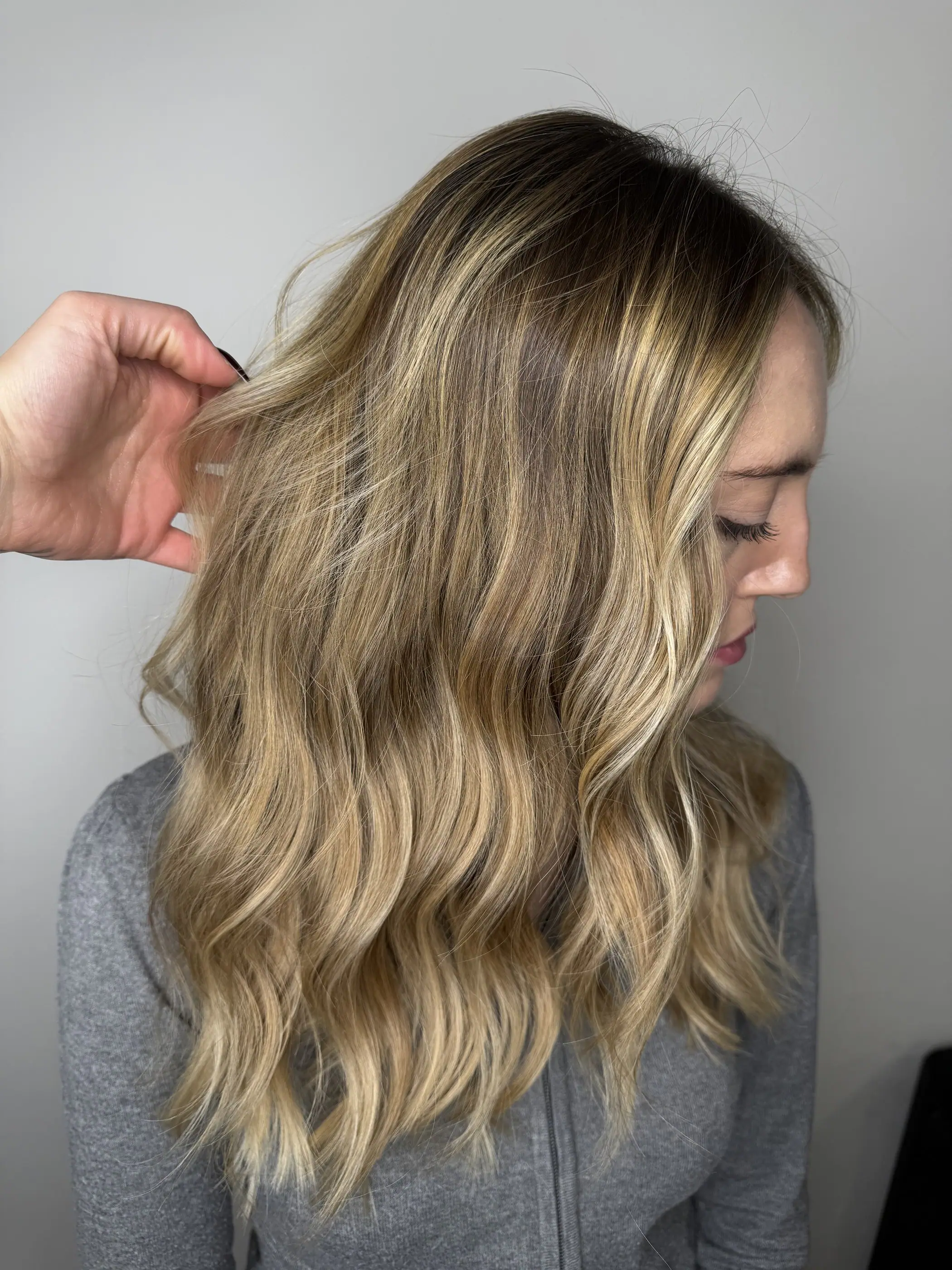 Capelli biondi mossi con radice scura sfumata, visti di profilo