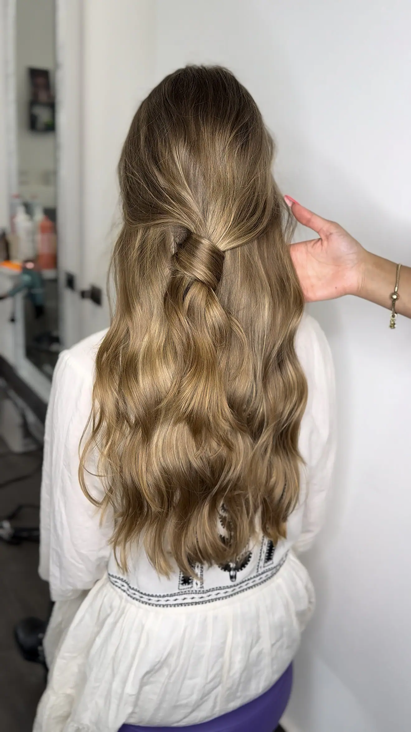 Lunghi capelli biondi con onde morbide, sistemati a mano, visti di spalle